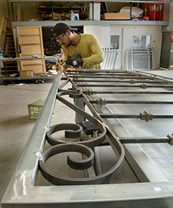 Serg is welding the Parisian driveway gate with scrolls, knuckles and arch.